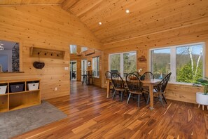 A wooden interior with a dining area, wooden walls, and large windows. - Beautiful Comfortable Modern Home on a Quiet Lake surrounded by wilderness. (Baysville)