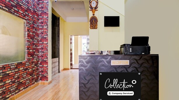 A reception area with a brick wall, a reception desk labeled 'RECEPTION,' and a sign indicating 'Collection Company-Serviced.' - Classic With Balcony Ganeshguri Nayanpur (Guwahati)