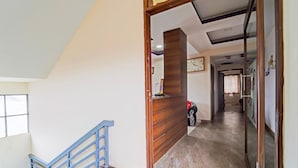 A staircase with a blue handrail leading to a landing with a wooden reception desk. - Deluxe G K Building (Thindukkal)