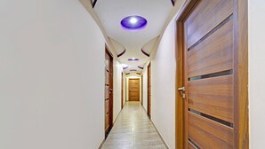 A hallway with wooden doors, a tiled floor, and recessed lighting. - Deluxe G K Building (Thindukkal)