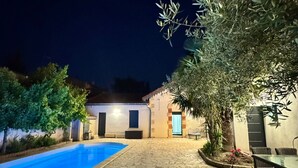 Una piscina, un patio y un edificio con una puerta y ventanas.