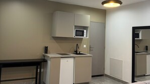 Una cocina moderna con electrodomésticos integrados, un comedor con mesa y sillas, y una sala de estar con sofá.
