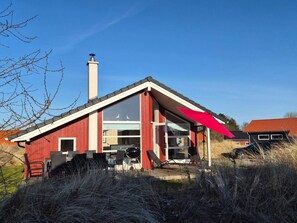 A red house with a chimney, large windows, and a deck area. - 4 Star Holiday Home in Grossenbrode (Grossenbrode)