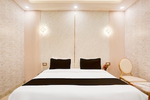 Ett hotellrum med en stor säng, ett litet bord, en stol och en spegel.