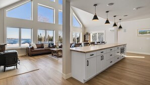 A spacious kitchen with large windows, a central island, and a cozy seating area.