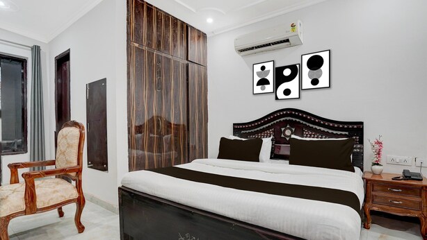 A bedroom with a bed, a chair, a wardrobe, and a bedside table. - Classic With Balcony Huda Market Sector 46 (Gurugram)