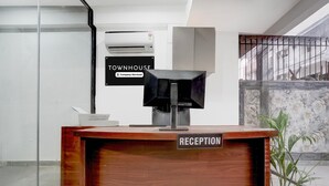 A reception desk with a 'RECEPTION' sign, a potted plant, and a 'TOWNHOUSE' sign in the background. - Classic With Balcony Huda Market Sector 46 (Gurugram)