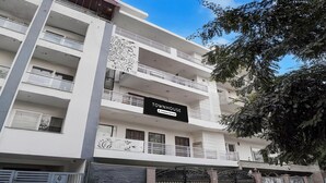 A multi-story building with balconies, a sign reading 'TOWNHOUSE & Company Service,' and gated entrances. - Classic With Balcony Huda Market Sector 46 (Gurugram)