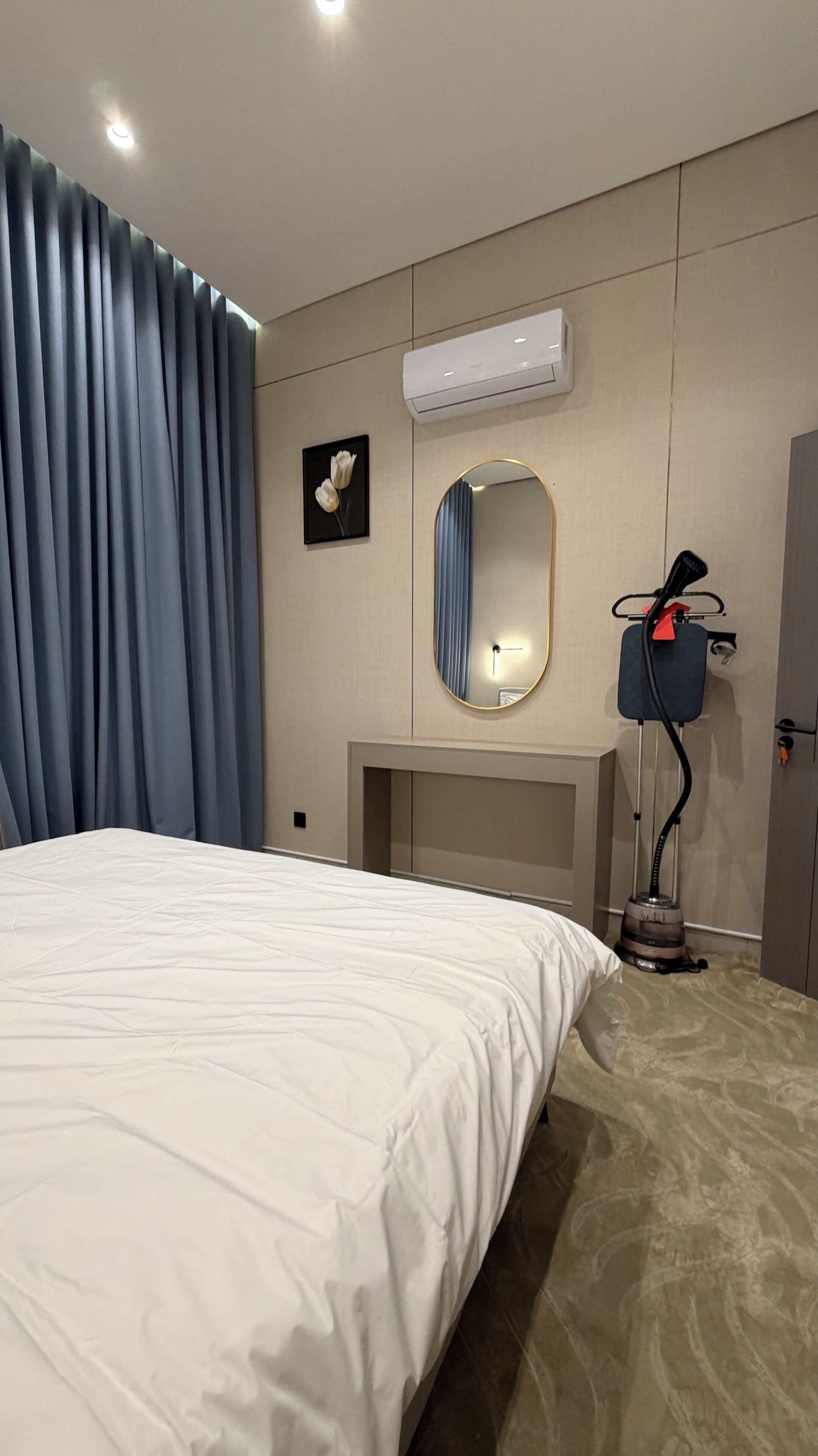 Ein Hotelzimmer mit einem Bett, einer Klimaanlage, einem Spiegel, einem Bilderrahmen und einem Staubsauger.