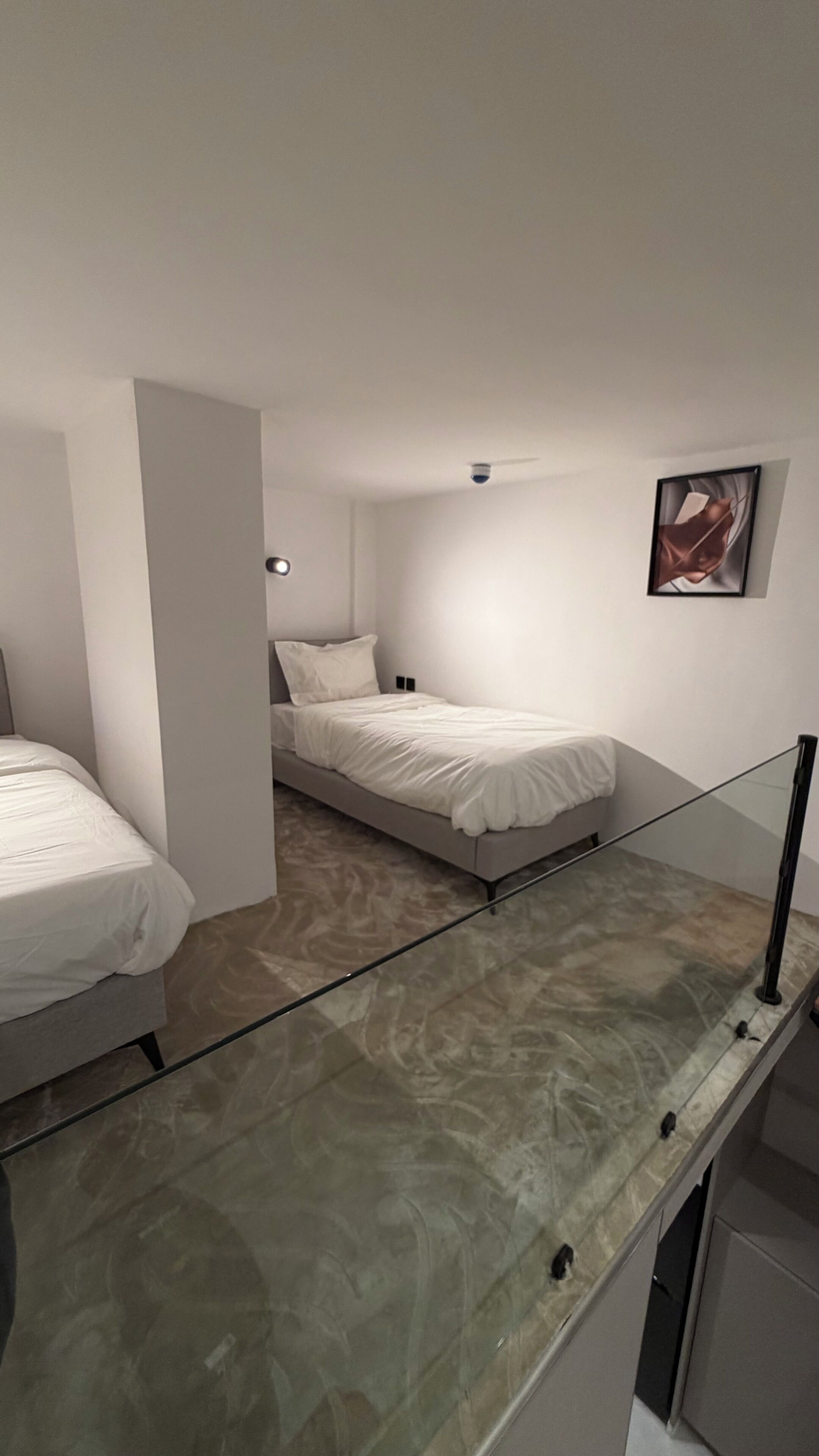 Un dormitorio moderno con una cama, una mesita de noche, un ventilador de techo y un cuadro en la pared.