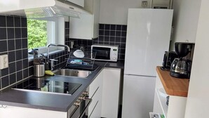 Eine kleine Küche mit Mikrowelle, Herd, Spüle und Kaffeemaschine.