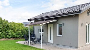 Ein modernes Haus mit überdachter Terrasse, einer Tür und einem Fenster.