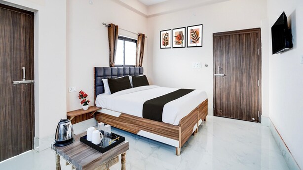 A hotel room with a bed, a TV, a wooden door, and a small table with a tray.