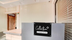 A reception desk with a sign indicating it's company-serviced. A wooden door is visible in the background.