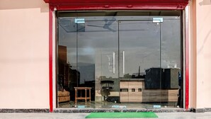 A hotel entrance with a glass door, a red awning, and a small wooden stool inside.