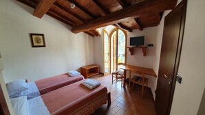 A room with two beds, a desk, a chair, a TV, and a door. - Hotel Terme Ristorante (Acquasanta Terme)