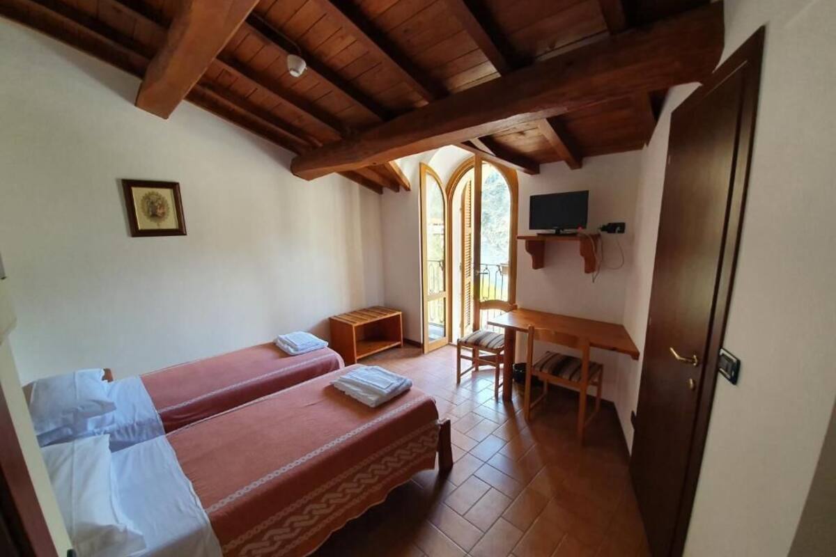Una habitación con dos camas, un escritorio, una silla, un televisor y una puerta.