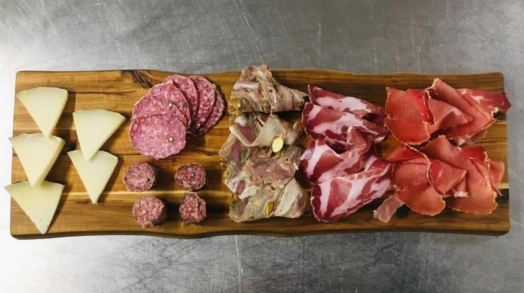 A wooden board with various types of cured meats and cheese.
