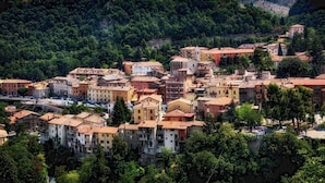 A hillside town with buildings, a bridge, and dense greenery. - Hotel Terme Ristorante (Acquasanta Terme)