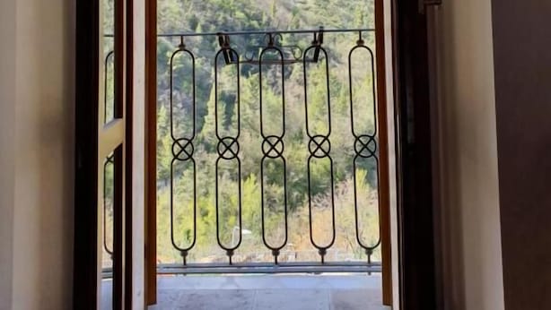 A balcony with a wrought iron railing, a view of a mountain, and an arched doorway. - Hotel Terme Ristorante (Acquasanta Terme)