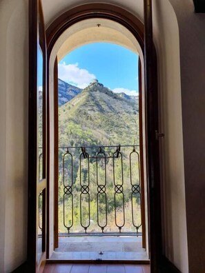 A balcony with a wrought iron railing, a view of a mountain, and an arched doorway. - Hotel Terme Ristorante (Acquasanta Terme)
