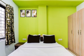 A room with a bed, a wardrobe, a window with curtains, and wall art. - Saver Singlerelax Guest House (Durgapur)