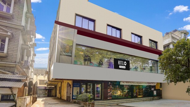 Un hotel moderno con fachada de vidrio, un detalle rojo en el techo y un letrero que dice 'HOTEL'.
