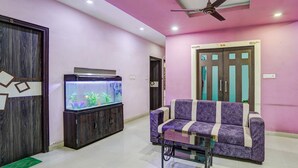 Una sala de estar con un sofá, un acuario y un ventilador de techo.