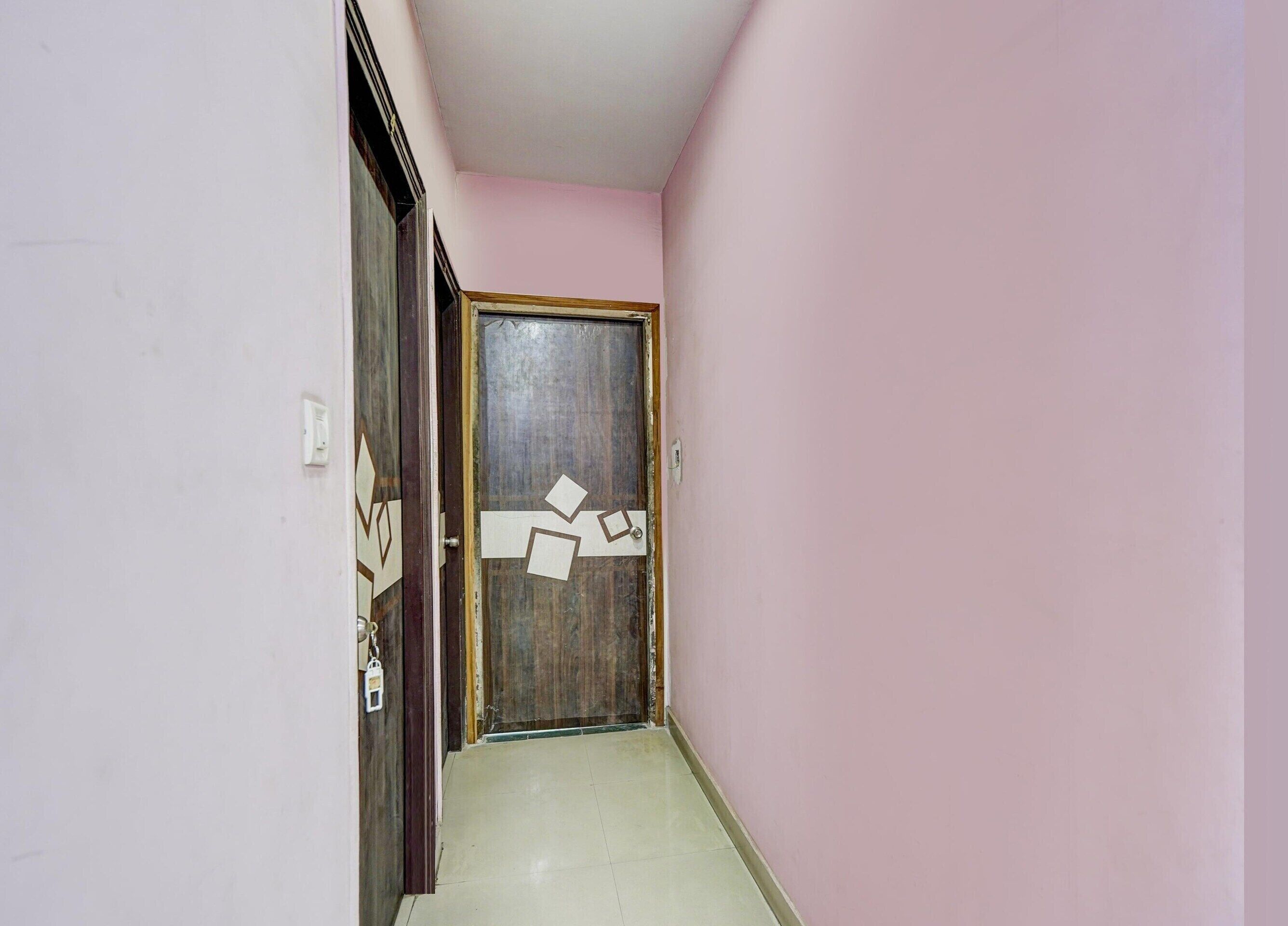 A narrow hallway with a wooden door and a light switch on the wall.