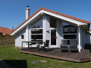 Ein Haus mit Terrasse, großen Fenstern und Schornstein.