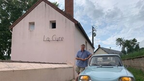 Ein Gebäude mit der Aufschrift 'La Cure' und einem Oldtimer davor geparkt.