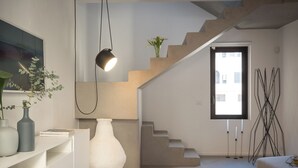 A modern interior with a staircase, a white vase, and a hanging light fixture. - Backhoe Suite (Taormina)