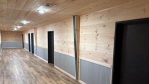 A long hallway with wooden walls and floors, multiple doors, and a ceiling with recessed lighting. - 4 Corners Event Center (Elk Falls)