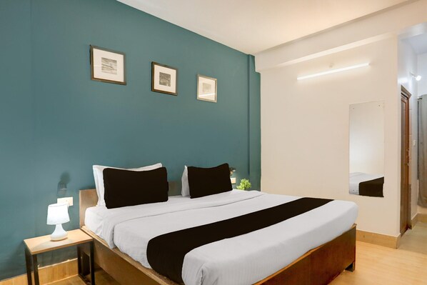 Un dormitorio con cama, mesita de noche y cuadros en la pared.