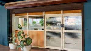 Una façana de fusta, grans finestres de vidre i plantes en testos.