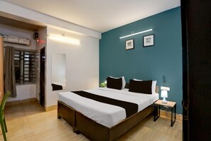 Un dormitorio con cama, mesita de noche, lámpara y ventana con cortinas.