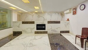 A reception area with marble flooring, a reception desk, a clock, and an air conditioning unit. - Super Deluxe Roomhotel Kuber Inn (Dhanbad)