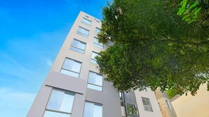 A modern building with multiple windows and a tree in the foreground. - Super Deluxe Roomhotel Kuber Inn (Dhanbad)