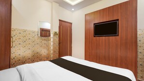 Een hotelkamer met een bed, een aan de muur bevestigde televisie, een deur en een behang met een patroon.