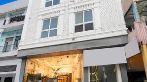 Een meerlaags gebouw met een restaurant of café op de begane grond, grote ramen en een trap naar een bovenverdieping.