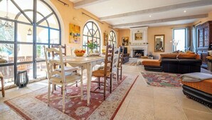 A spacious living room with a fireplace, large windows, and a dining area with chairs and a table. - Villa with views of the Alpilles and Luberon mountains (Mallemort)