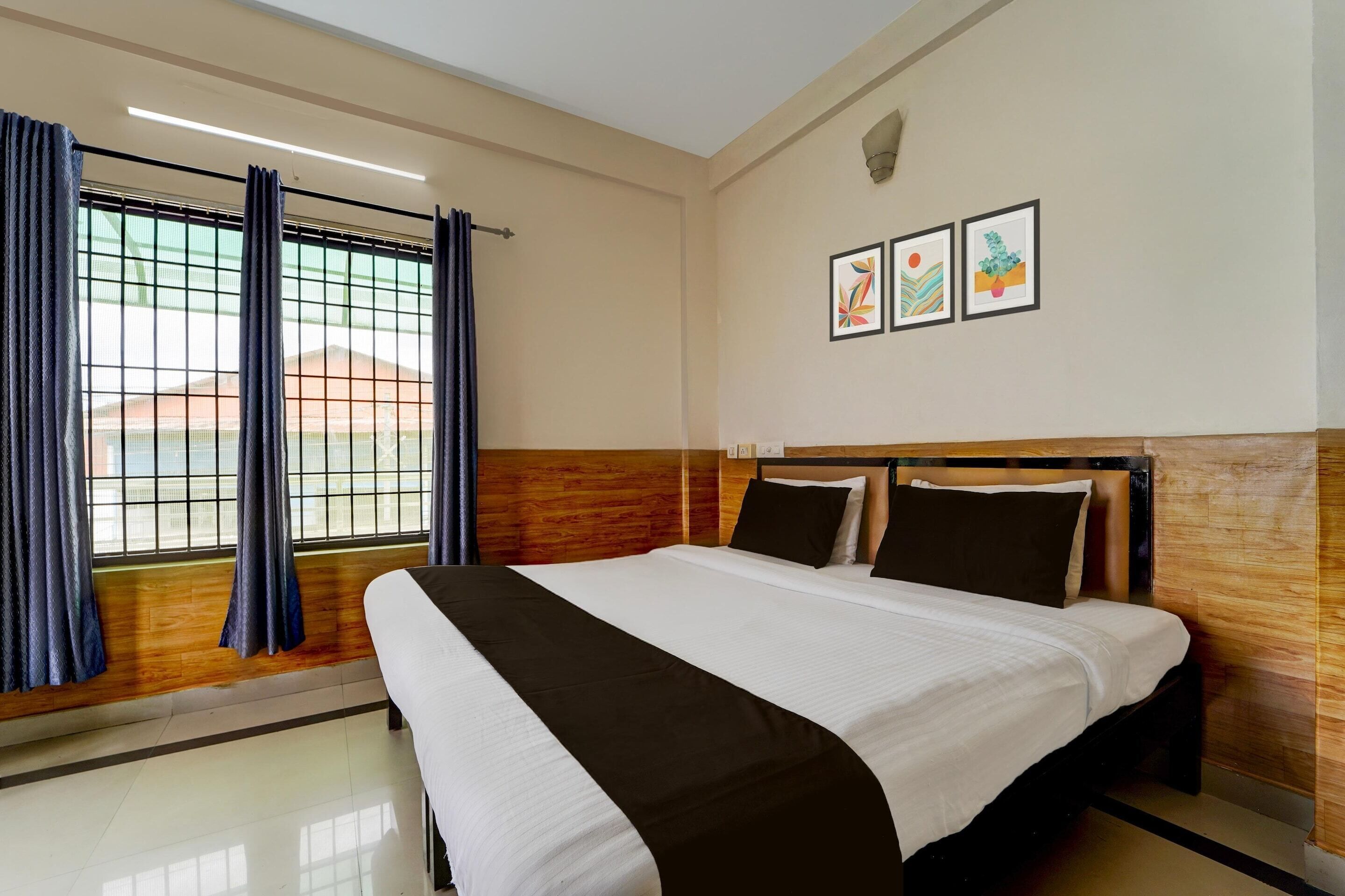A hotel room with a bed, curtains, a window, and artwork on the wall.
