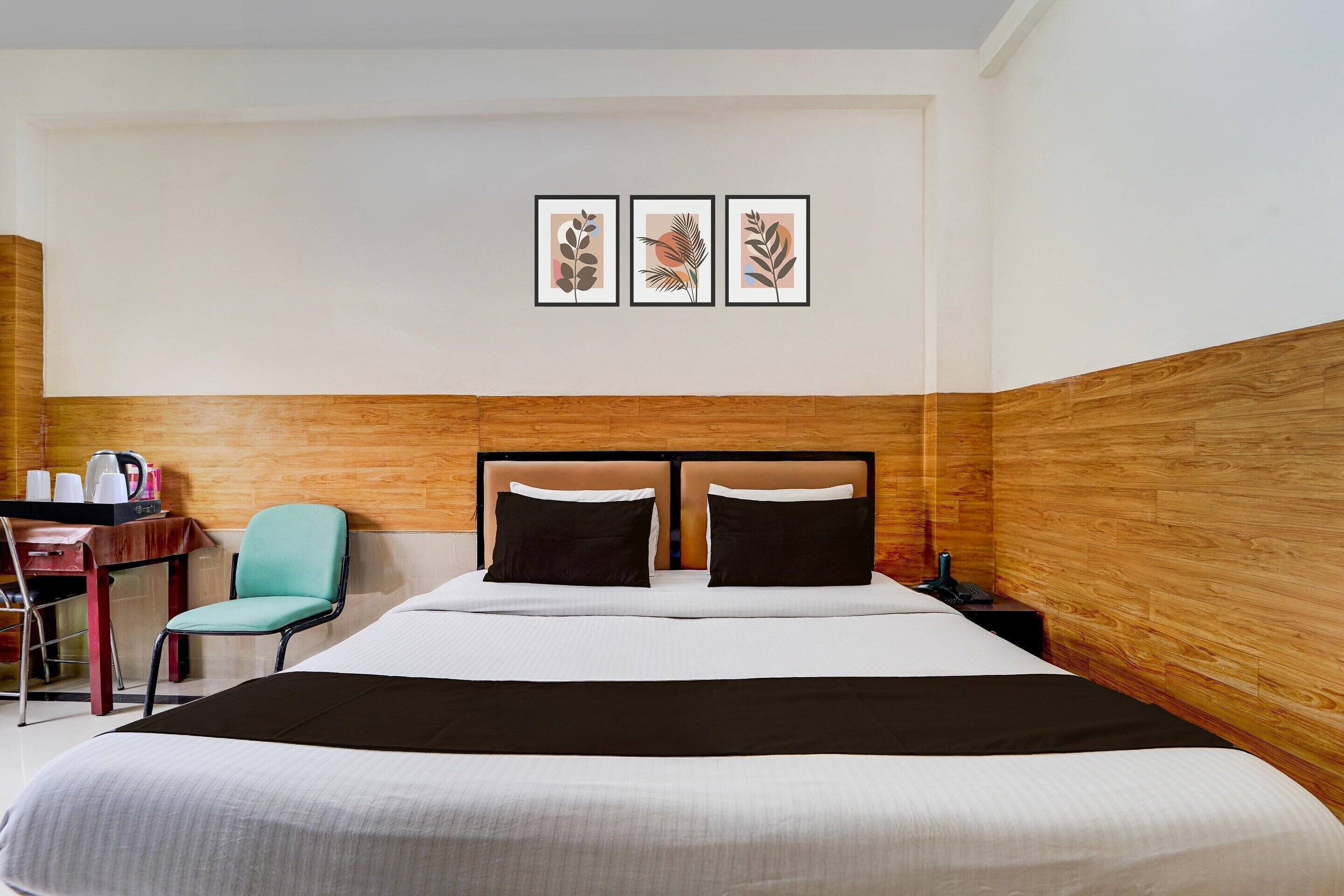 Habitación de hotel con cama, escritorio y silla, y cuadros en la pared.