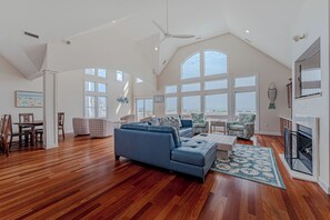 Een ruime woonkamer met een hoge plafond, grote ramen en een moderne keuken.