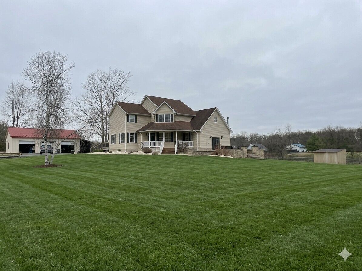 A two-story house with a front porch, a garage, and a well-maintained lawn.