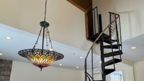 Ein geräumiger Wohnbereich mit hoher Decke, einer Wendeltreppe und einer Hängeleuchte.