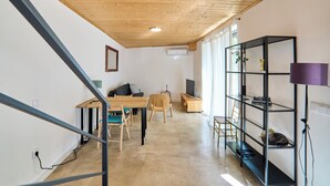 A modern interior with a wooden ceiling, a dining area with a table and chairs, a black shelving unit, and a television. - 2-bedroom villa in beautiful Faro with cool AC breeze (Faro)