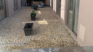 A narrow courtyard with tiled flooring, potted plants, and a bench. - 2-bedroom villa in beautiful Faro with cool AC breeze (Faro)