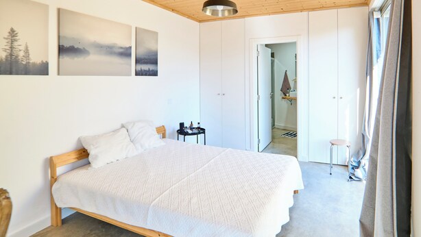 A bedroom with a wooden bed, a hanging light fixture, and a view of a bathroom. - 2-bedroom villa in beautiful Faro with cool AC breeze (Faro)
