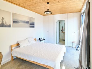Un dormitorio con cama de madera, una lámpara colgante y vistas al baño.